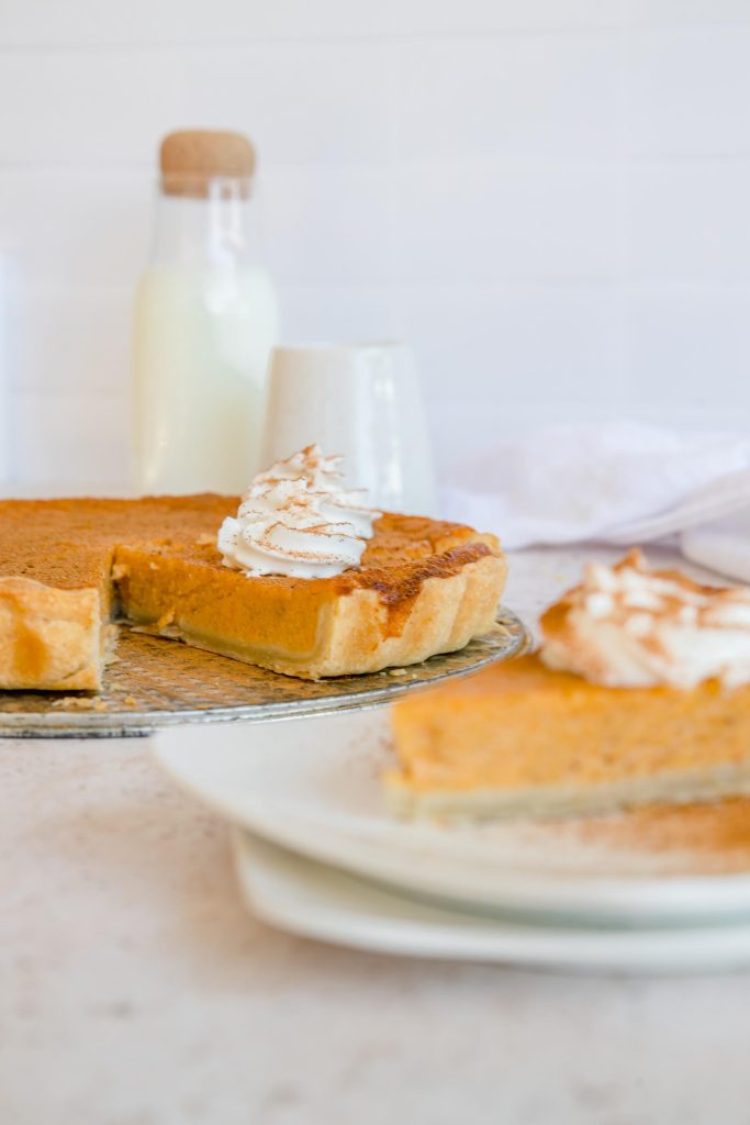 A slice of mouth-watering sweet potato pie, topped with whipped cream.