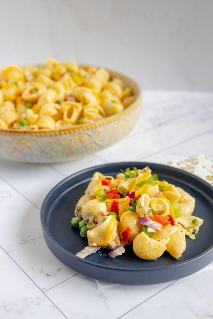 Close-up of a forkful of creamy, delicious macaroni salad, showcasing the perfectly cooked pasta and vibrant veggies