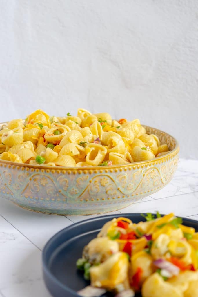 Close-up of a forkful of creamy, delicious macaroni salad, showcasing the perfectly cooked pasta and vibrant veggies