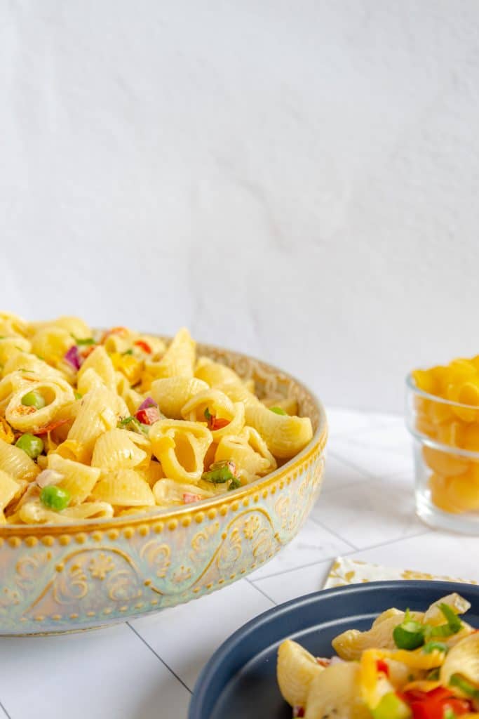 Close-up of a forkful of creamy, delicious macaroni salad, showcasing the perfectly cooked pasta and vibrant veggies