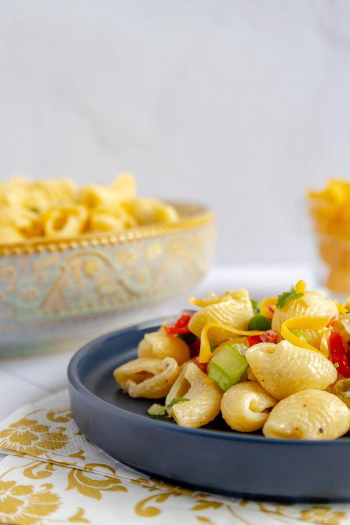 Close-up of a forkful of creamy, delicious macaroni salad, showcasing the perfectly cooked pasta and vibrant veggies