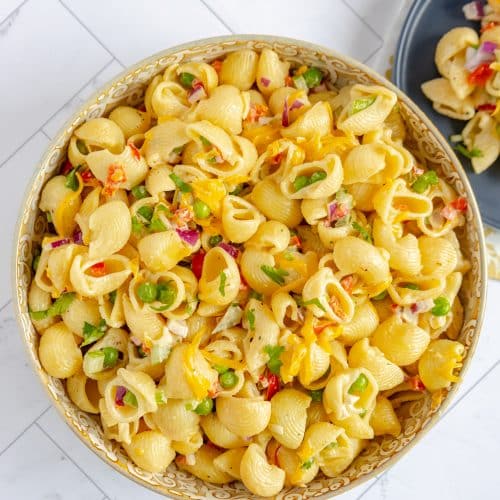 Close-up of a forkful of creamy, delicious macaroni salad, showcasing the perfectly cooked pasta and vibrant veggies