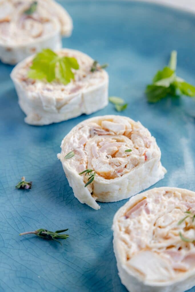 Freshly sliced chicken pinwheels laid out on a wooden cutting board, ready to serve at a gathering or party.