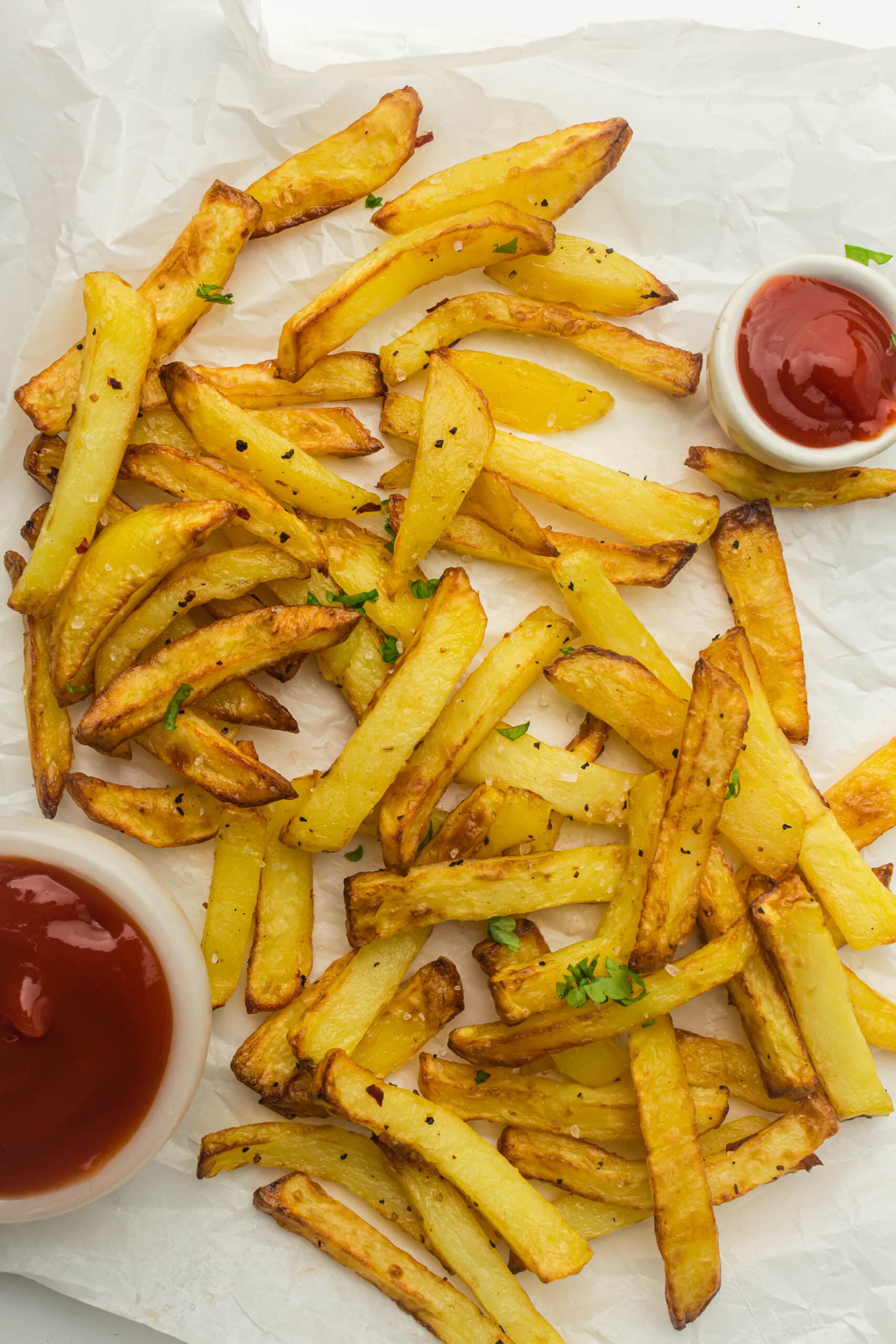 Crisp golden fries on parchment with a small pot of ketchup
