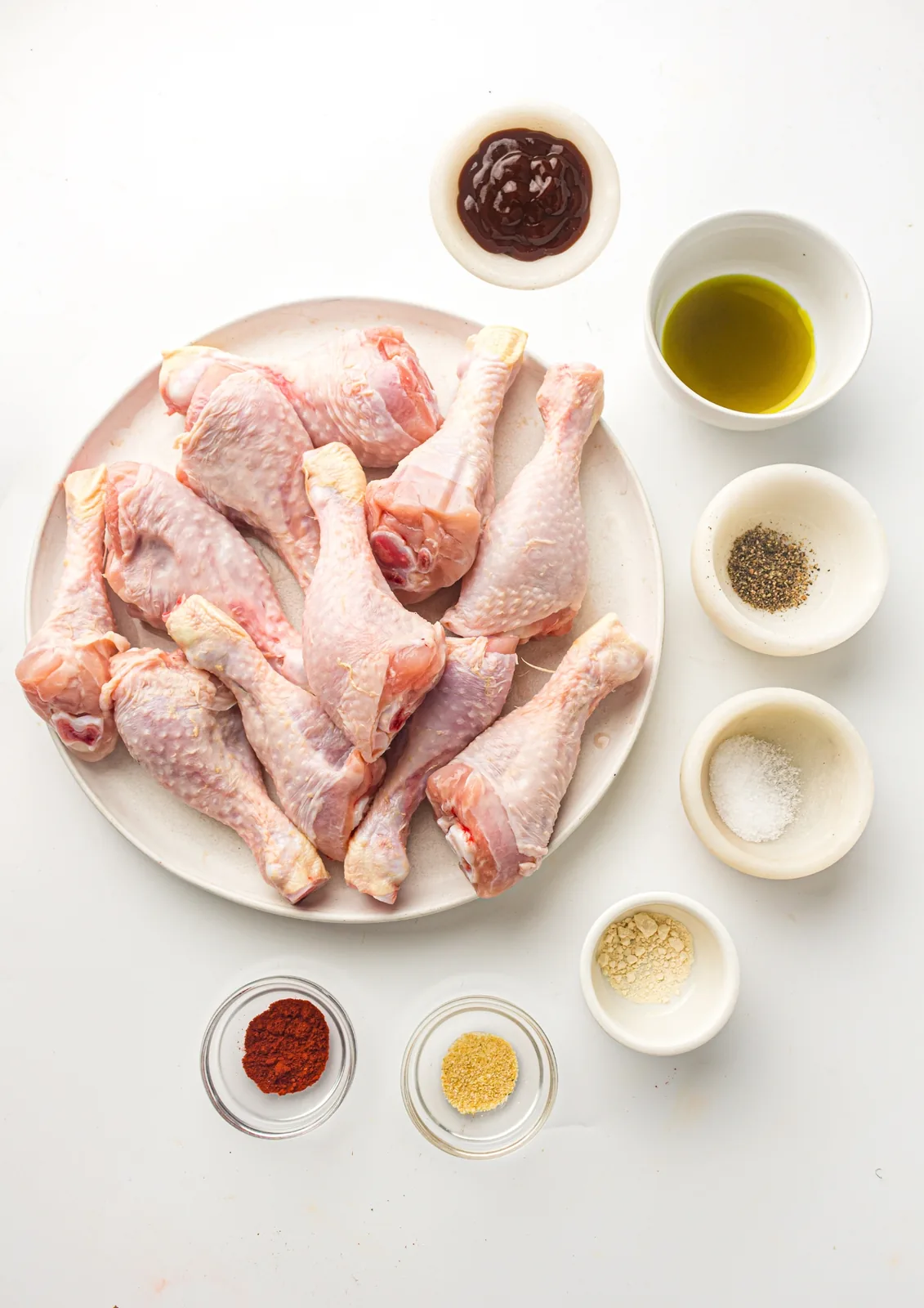 Ingredients for air fryer BBQ chicken: drumsticks, oil, paprika, garlic powder, onion powder, salt, pepper, and BBQ sauce