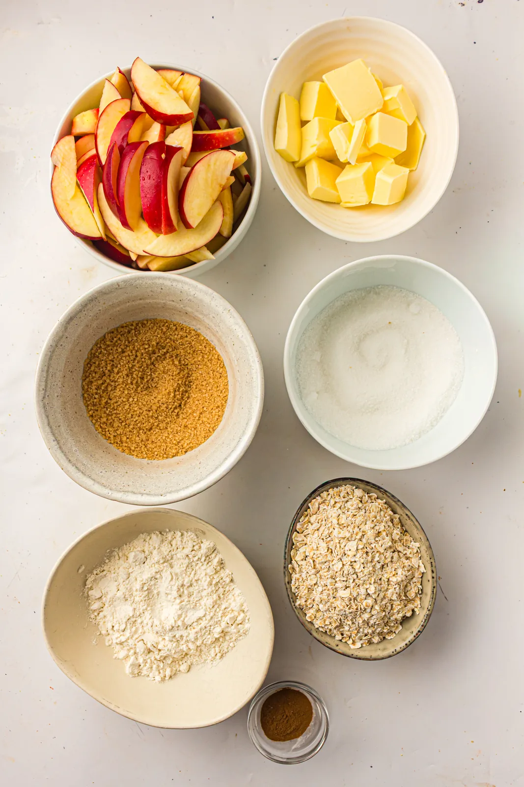 Ingredients for apple crisp: apples, rolled oats, flour, brown sugar, butter, and cinnamon