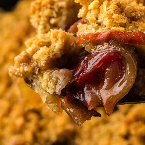 Spoonful of the finished dessert with baked apples and oat crumble