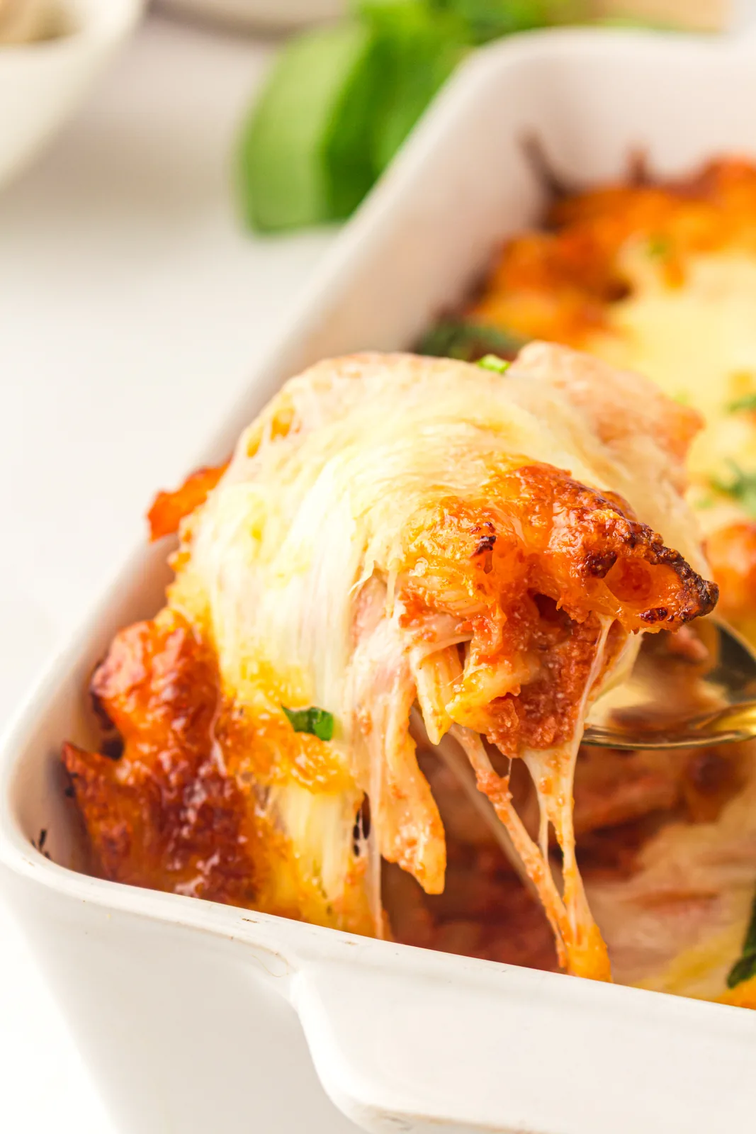 Gooey mozzarella stretching from a scoop of the cheesy pasta bake