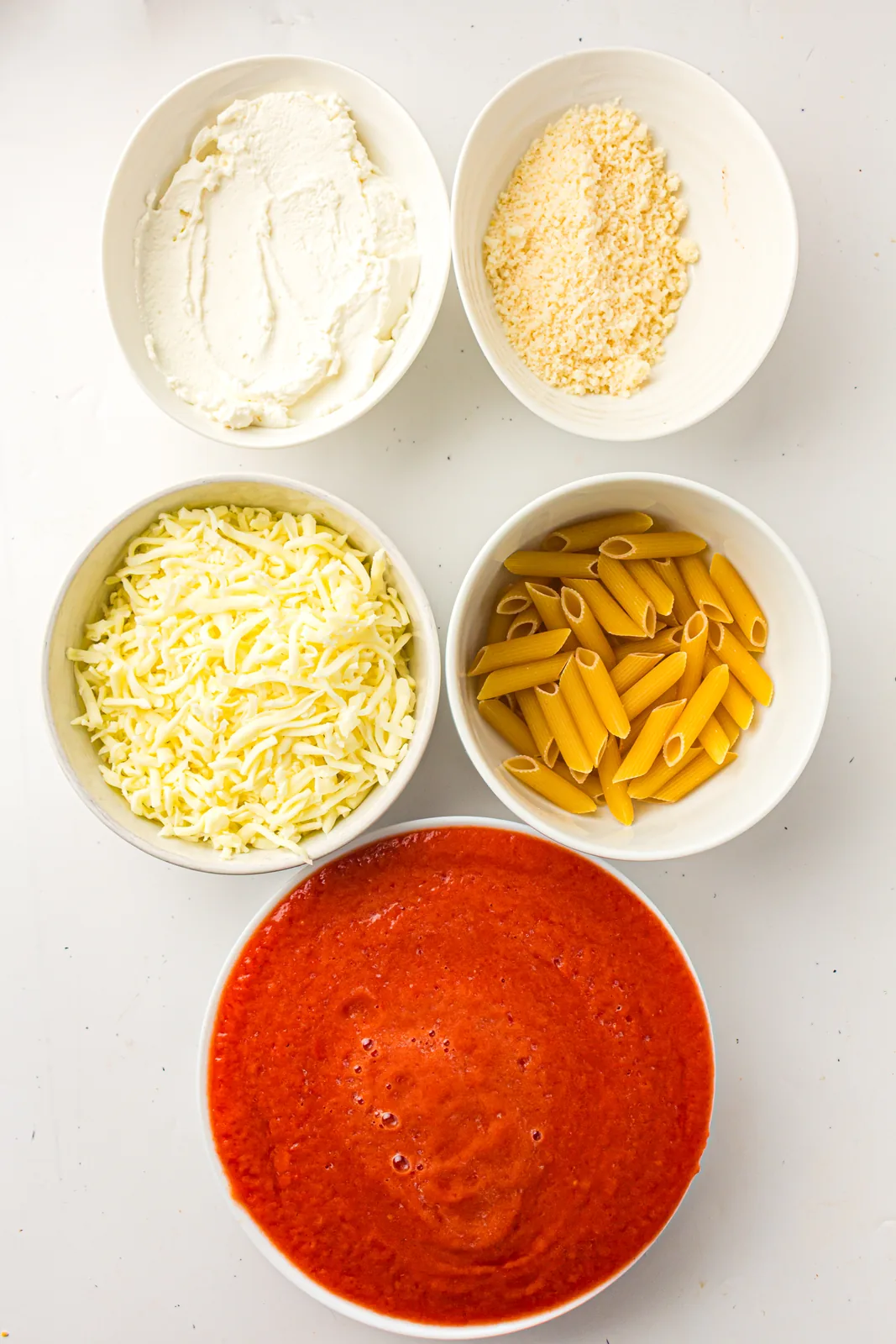 Ingredients for baked ziti: ziti pasta, marinara, ricotta, mozzarella, and parmesan