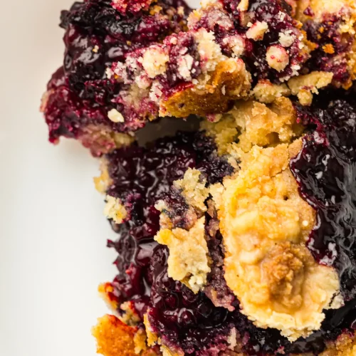 A close up of berry dump cake with bubbling fruit and golden topping