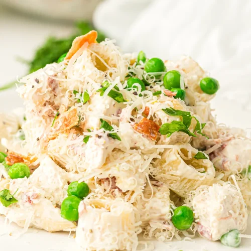 A plate of creamy chicken pasta salad with peas and bacon