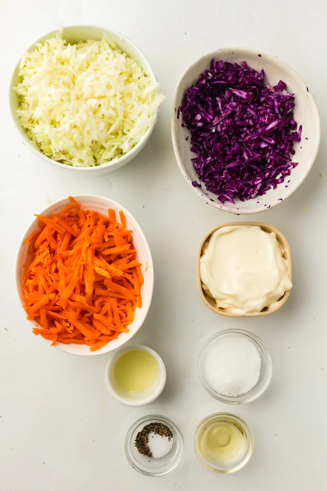 Ingredients for creamy coleslaw: green and red cabbage, carrots, mayonnaise, vinegar and lemon