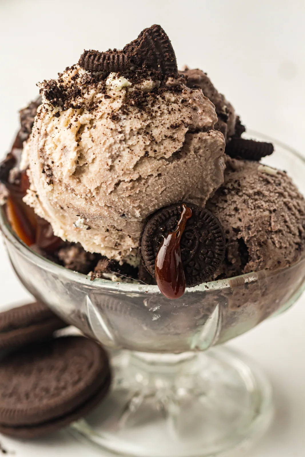 Cookies and cream ice cream in a glass coupe topped with Oreos and chocolate drizzle