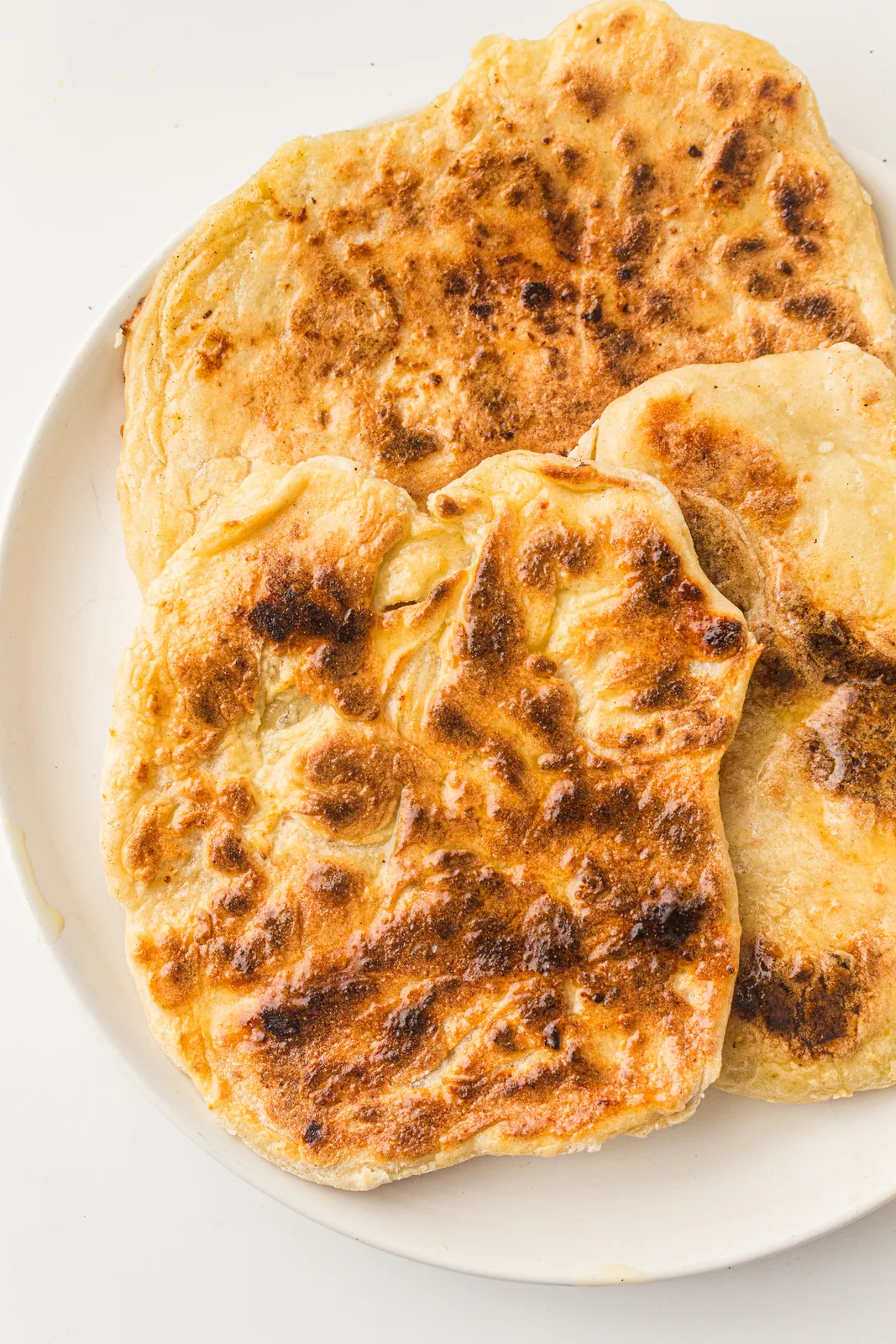 Golden cottage cheese flatbread rounds stacked on a white plate