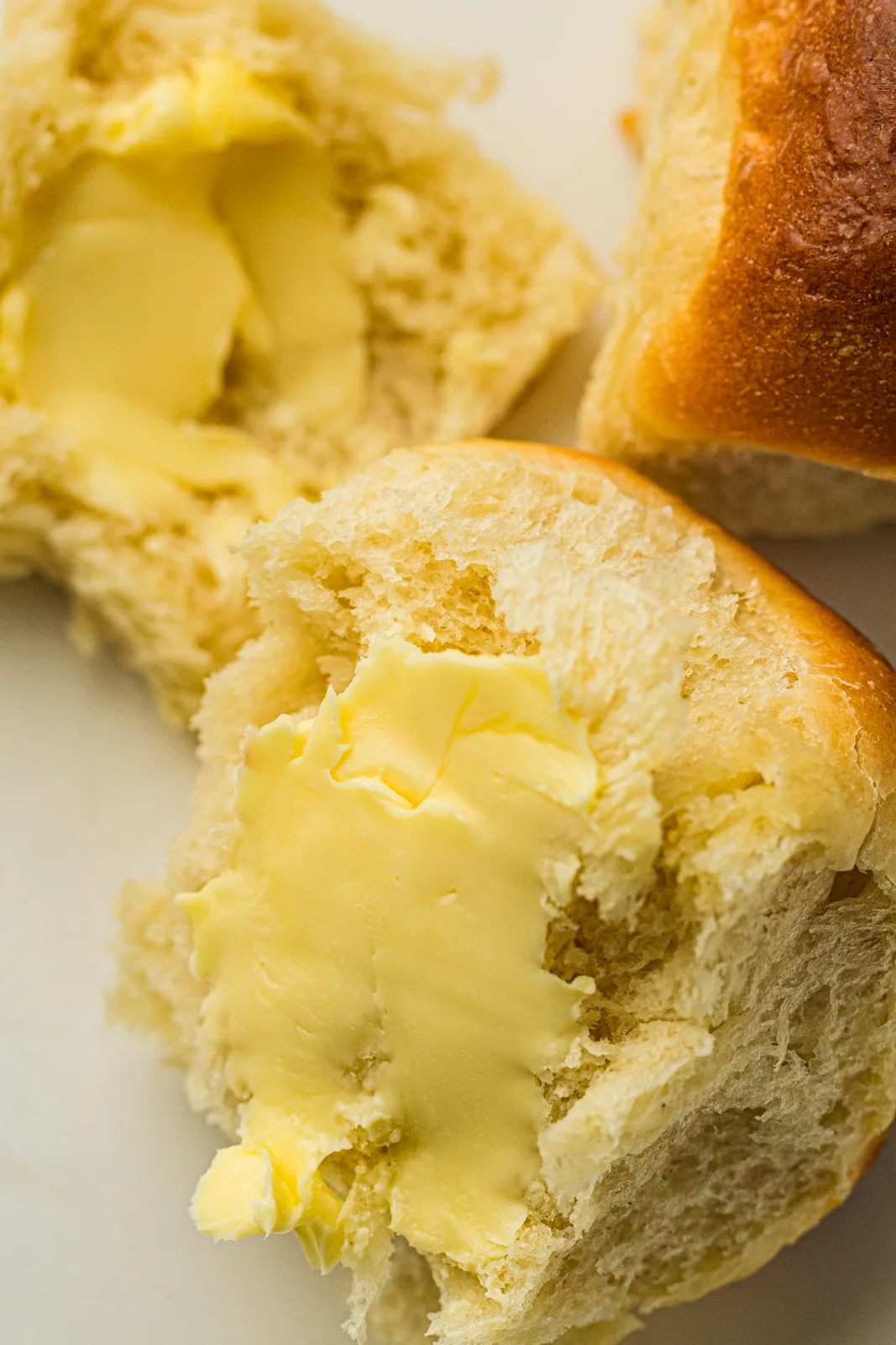 Fluffy golden rolls just touching in a buttered pan
