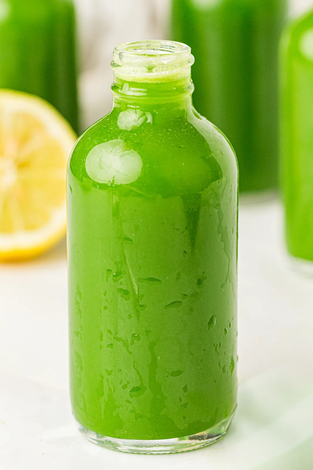 A bright, vibrant drink in a small glass bottle with lemon