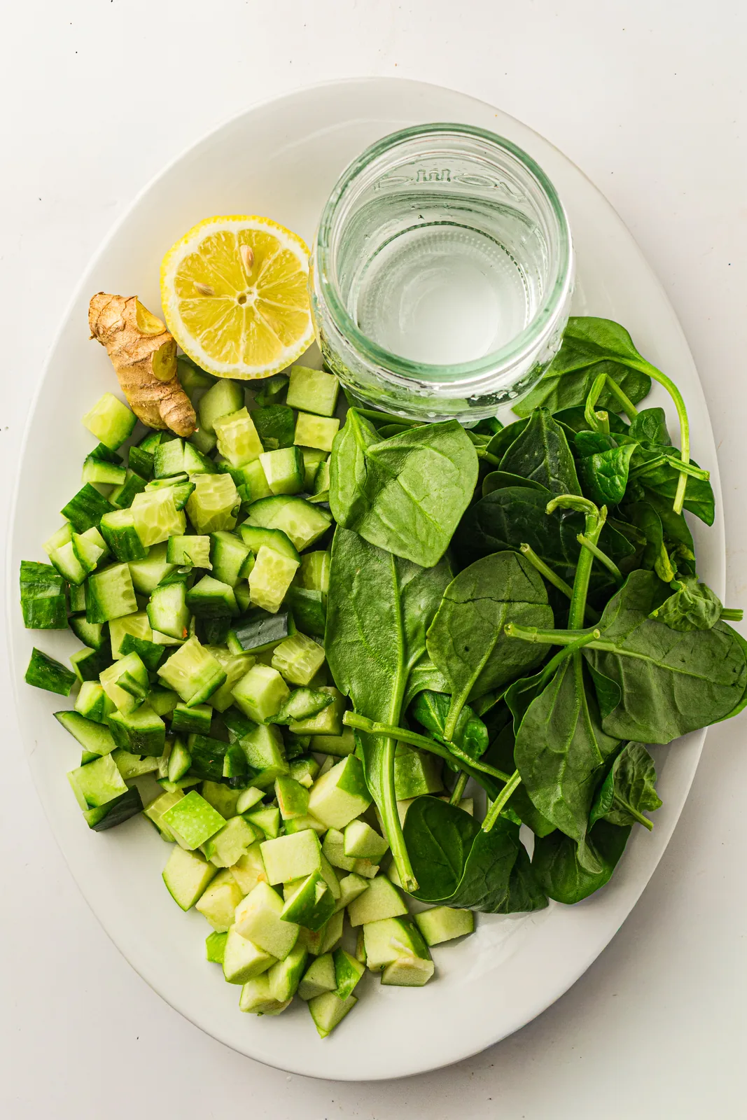 Green juice ingredients: spinach, cucumber, green apple, lemon, ginger, and water