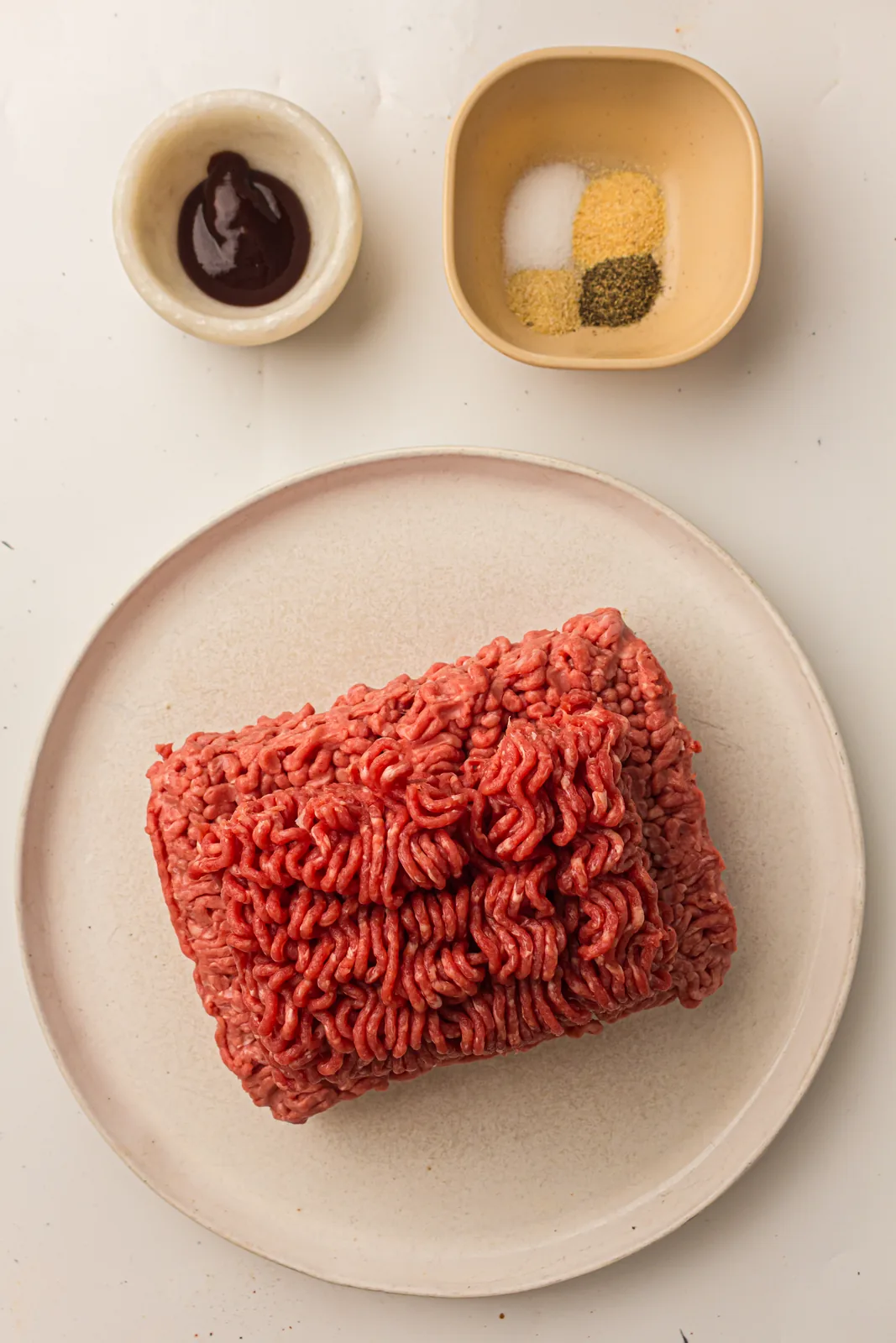 Ingredients for grilled burgers: ground beef, BBQ sauce, salt, pepper, garlic powder, and onion powder