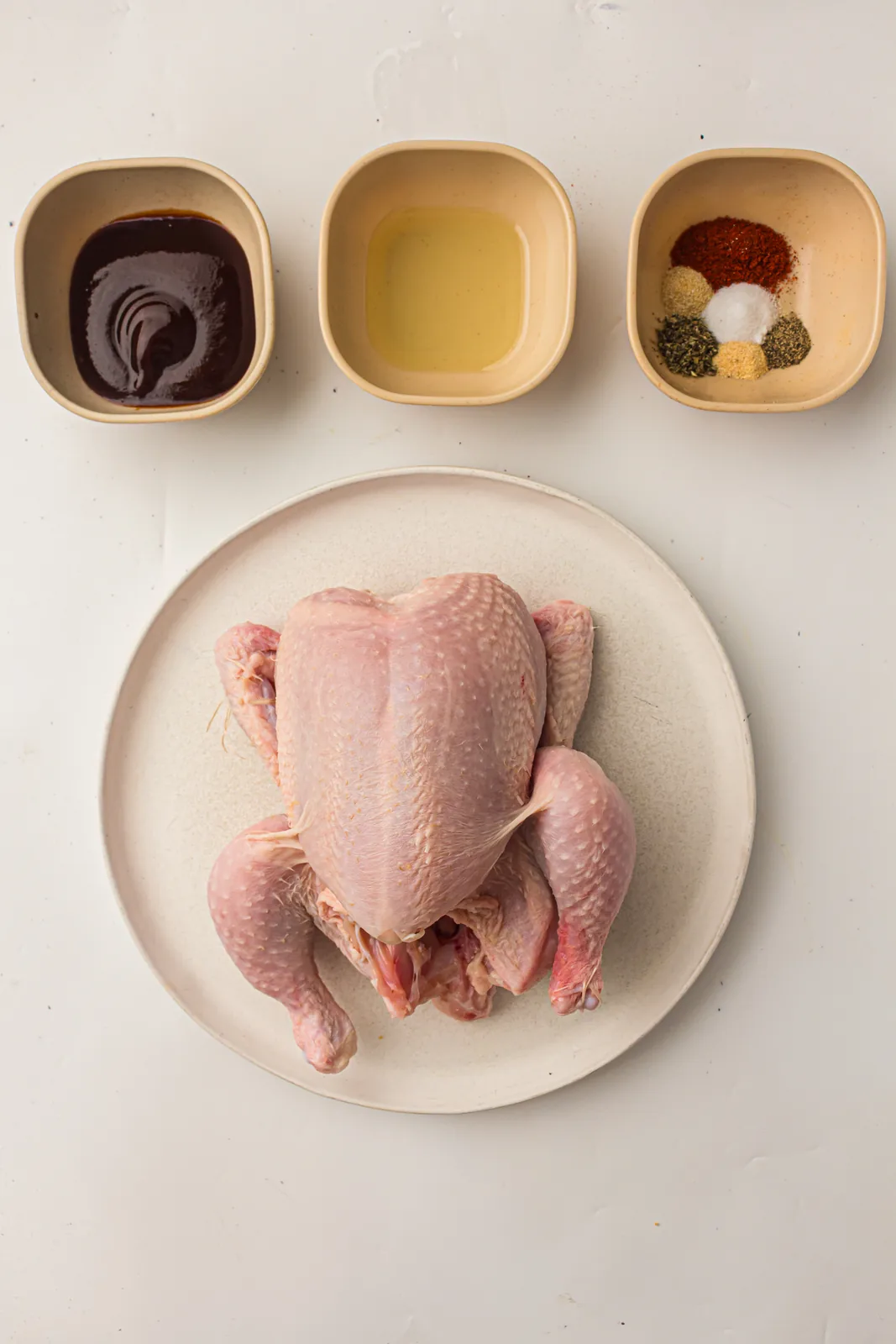Ingredients for grilled whole chicken: whole chicken, oil, smoked paprika, and dried spices