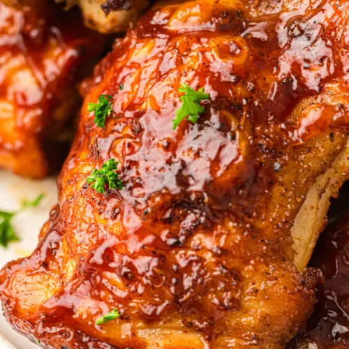 Close up of a BBQ-glazed smoked chicken thigh with crispy skin