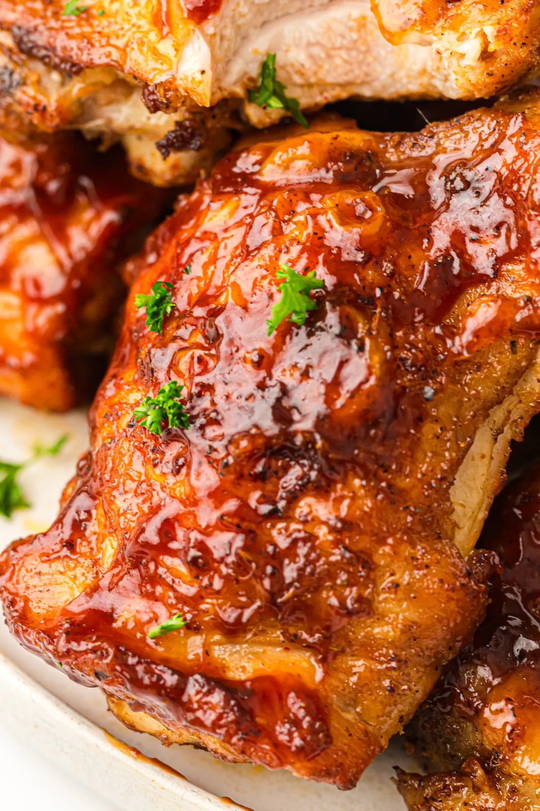 Close up of a BBQ-glazed smoked chicken thigh with crispy skin