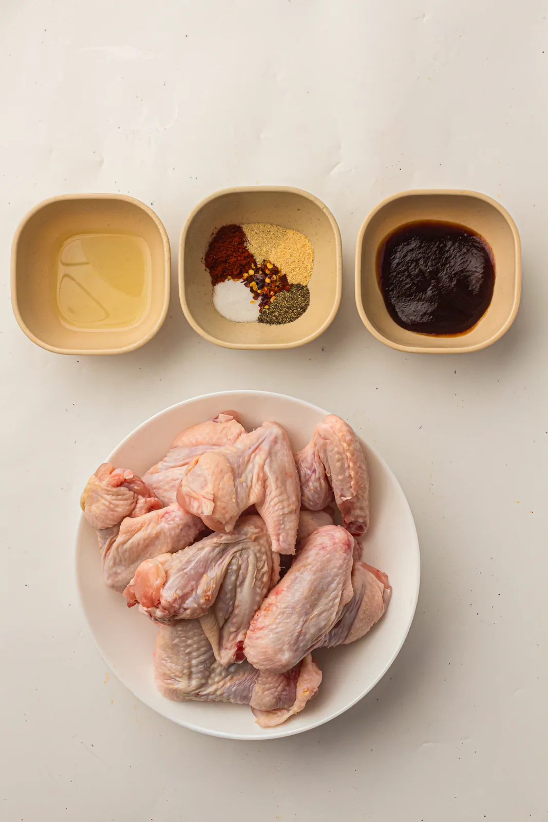 Ingredients for smoked chicken wings including dry rub, oil and BBQ sauce