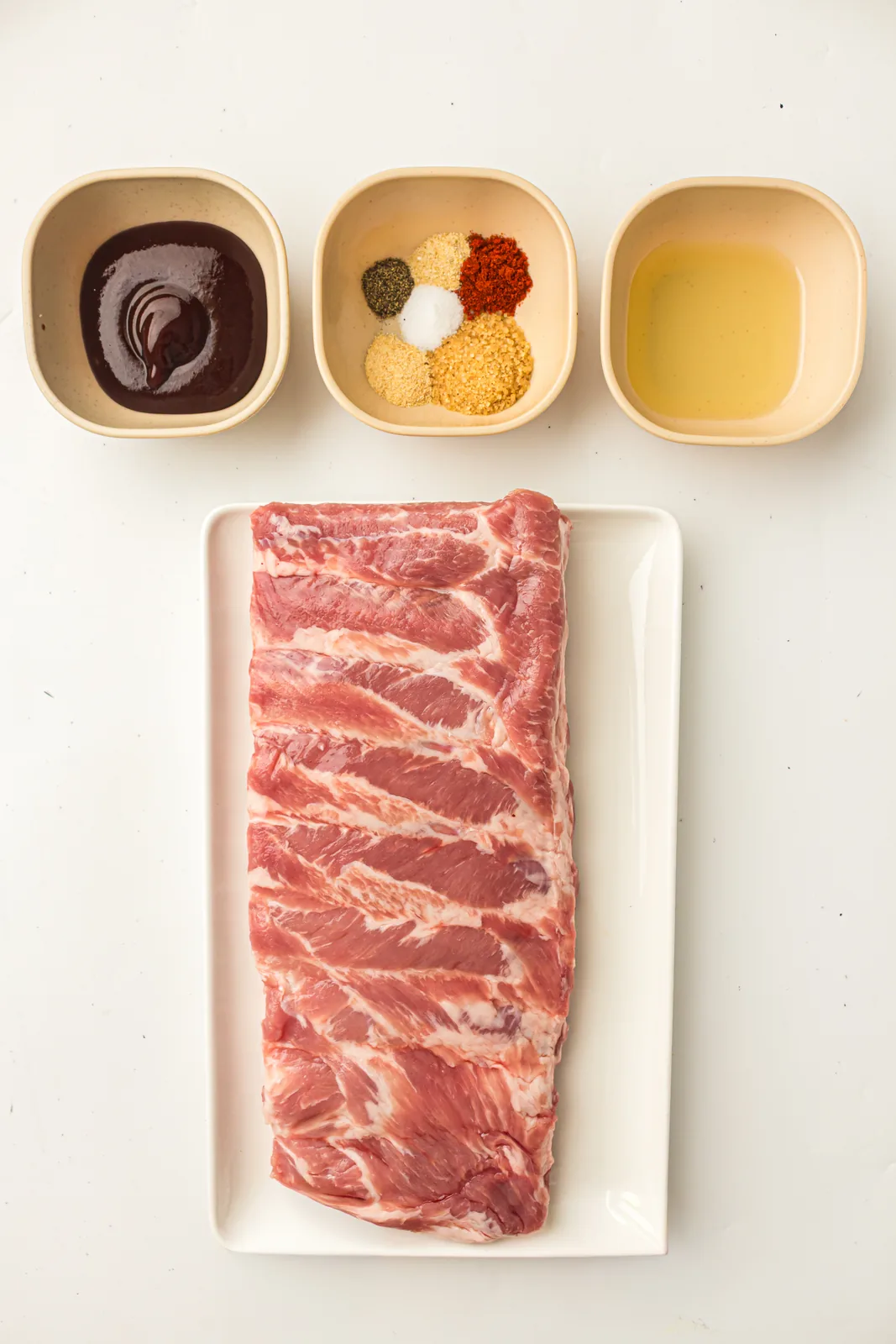 Ingredients for smoked ribs including a brown sugar dry rub and BBQ sauce
