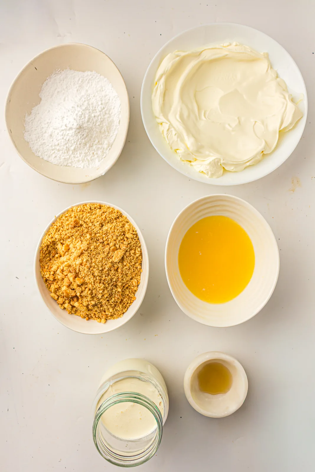 Ingredients for no bake cheesecake including cream cheese and graham crumbs