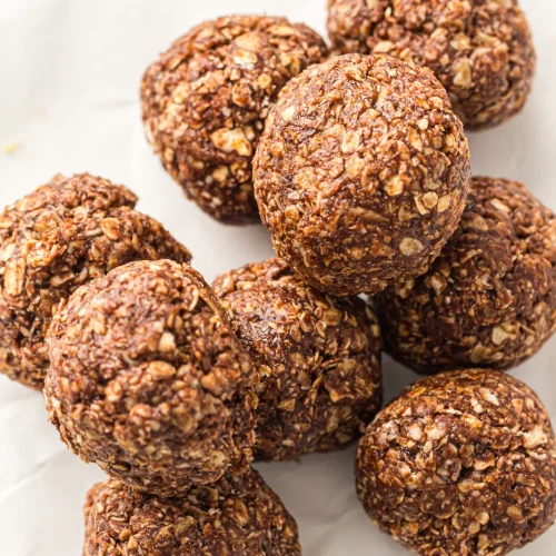 A pile of no-bake peanut butter oat balls on parchment