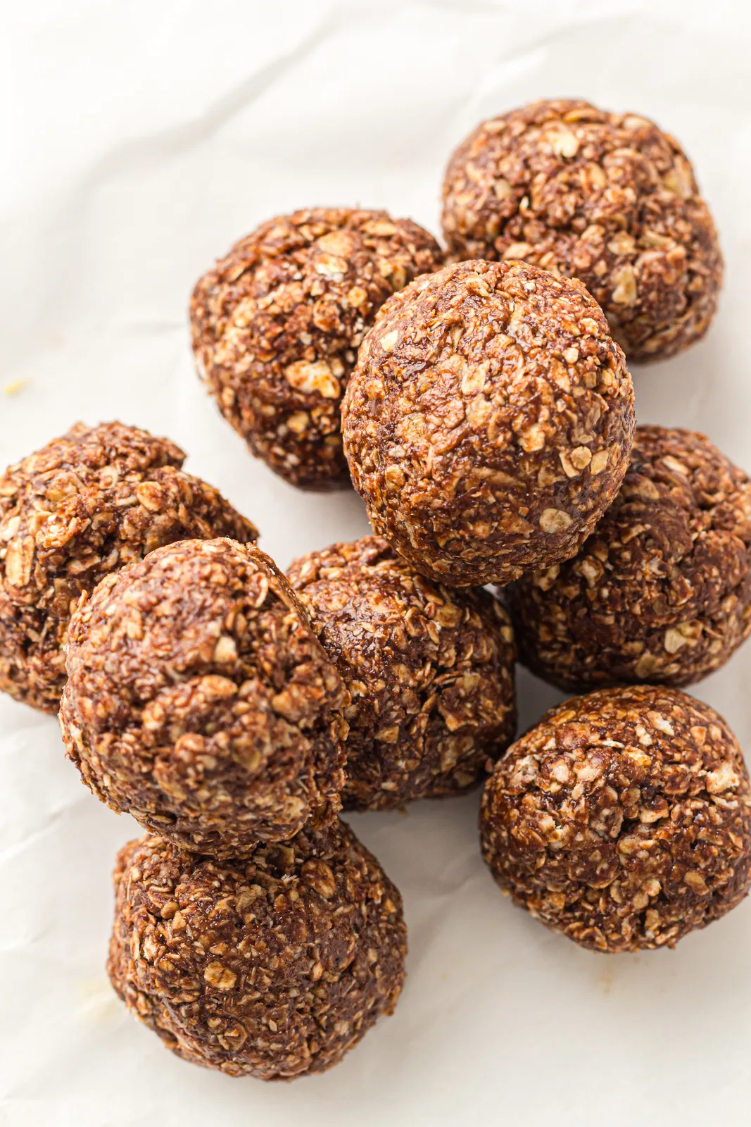 A pile of no-bake peanut butter oat balls on parchment