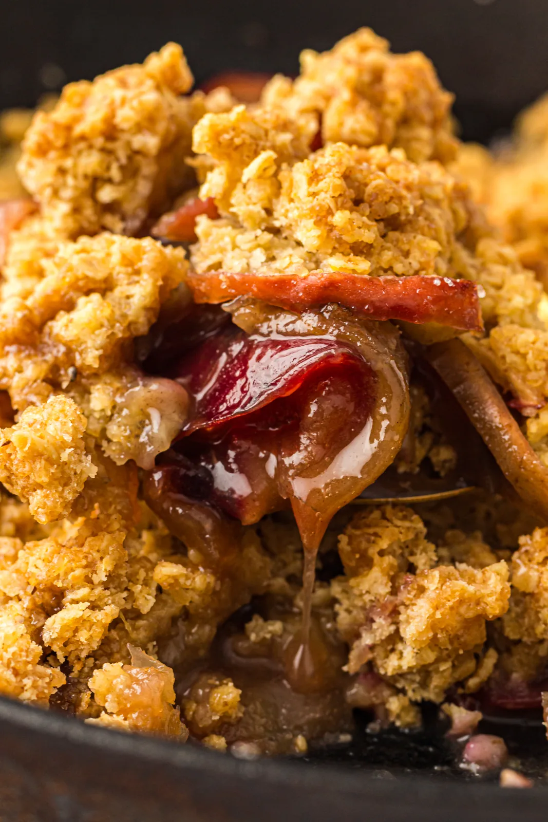 Close up of glossy baked cinnamon apples under a buttery oat topping