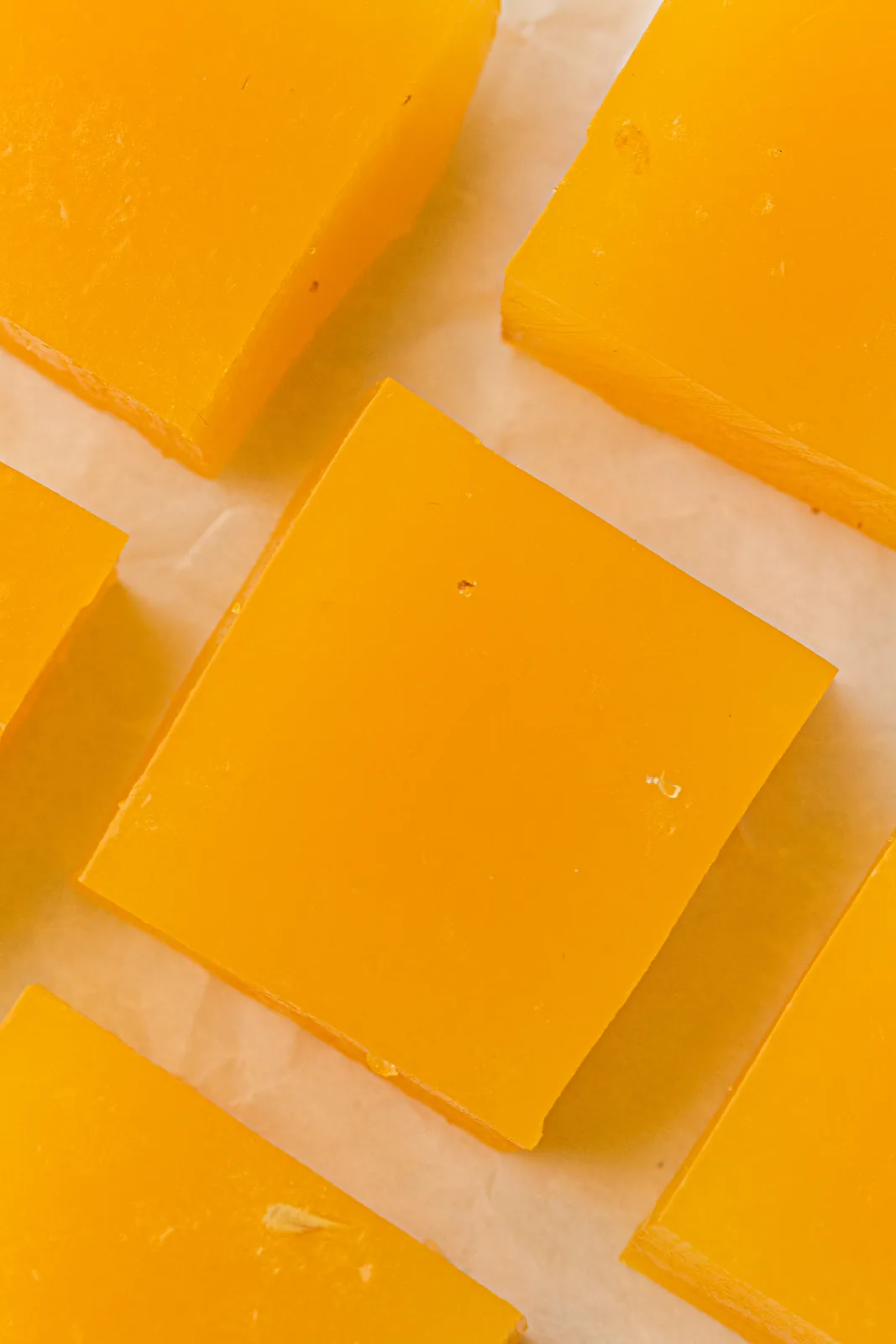 Bright orange jelly squares stacked on parchment paper