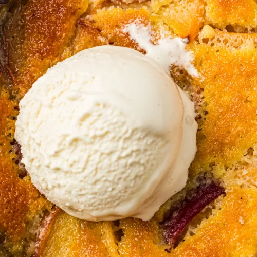 Peach cobbler with a scoop of vanilla ice cream in a skillet
