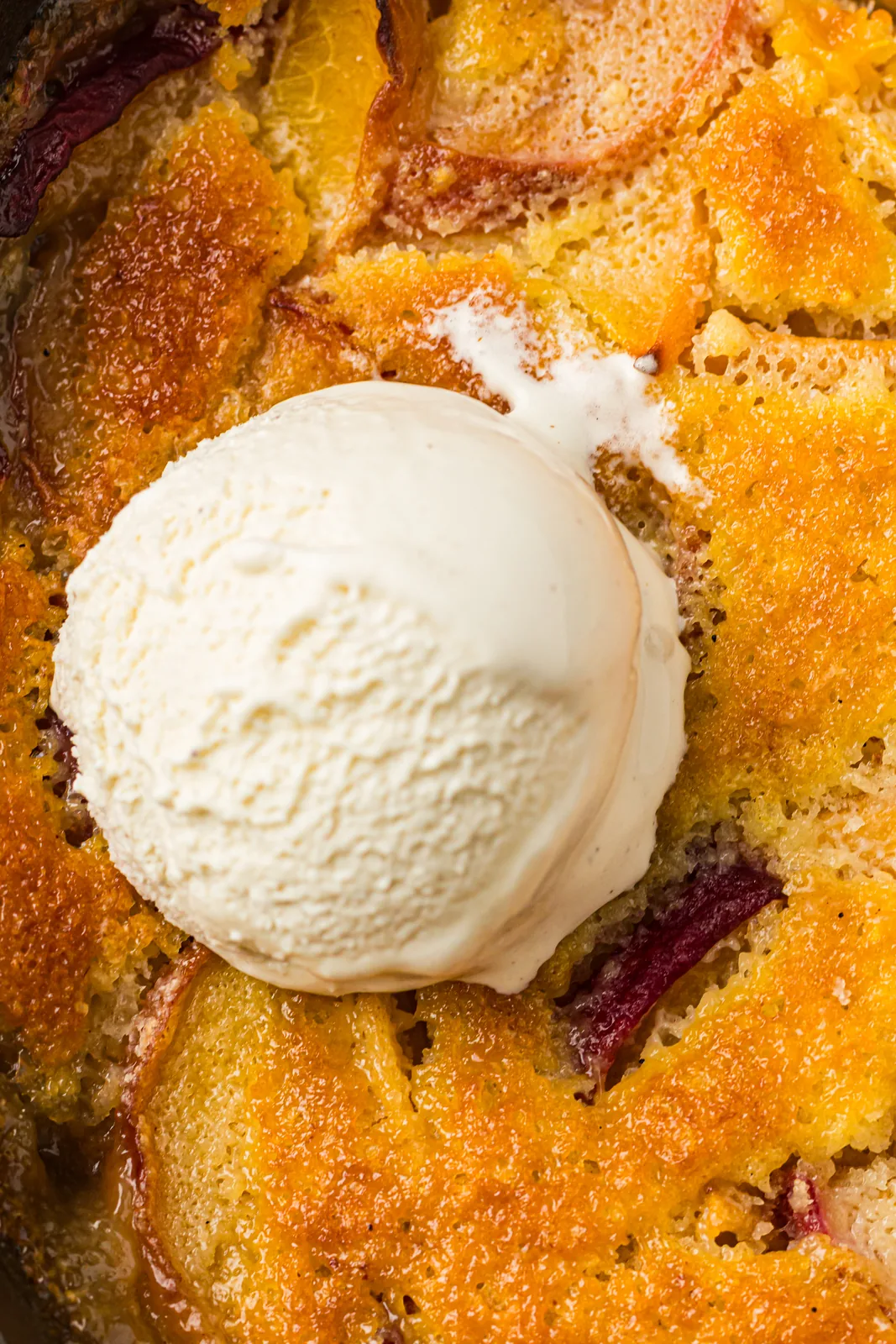 Peach cobbler with a scoop of vanilla ice cream in a skillet