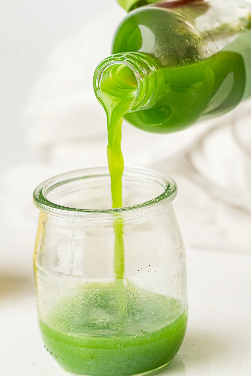 Pouring a vibrant drink shot from a bottle into a small glass