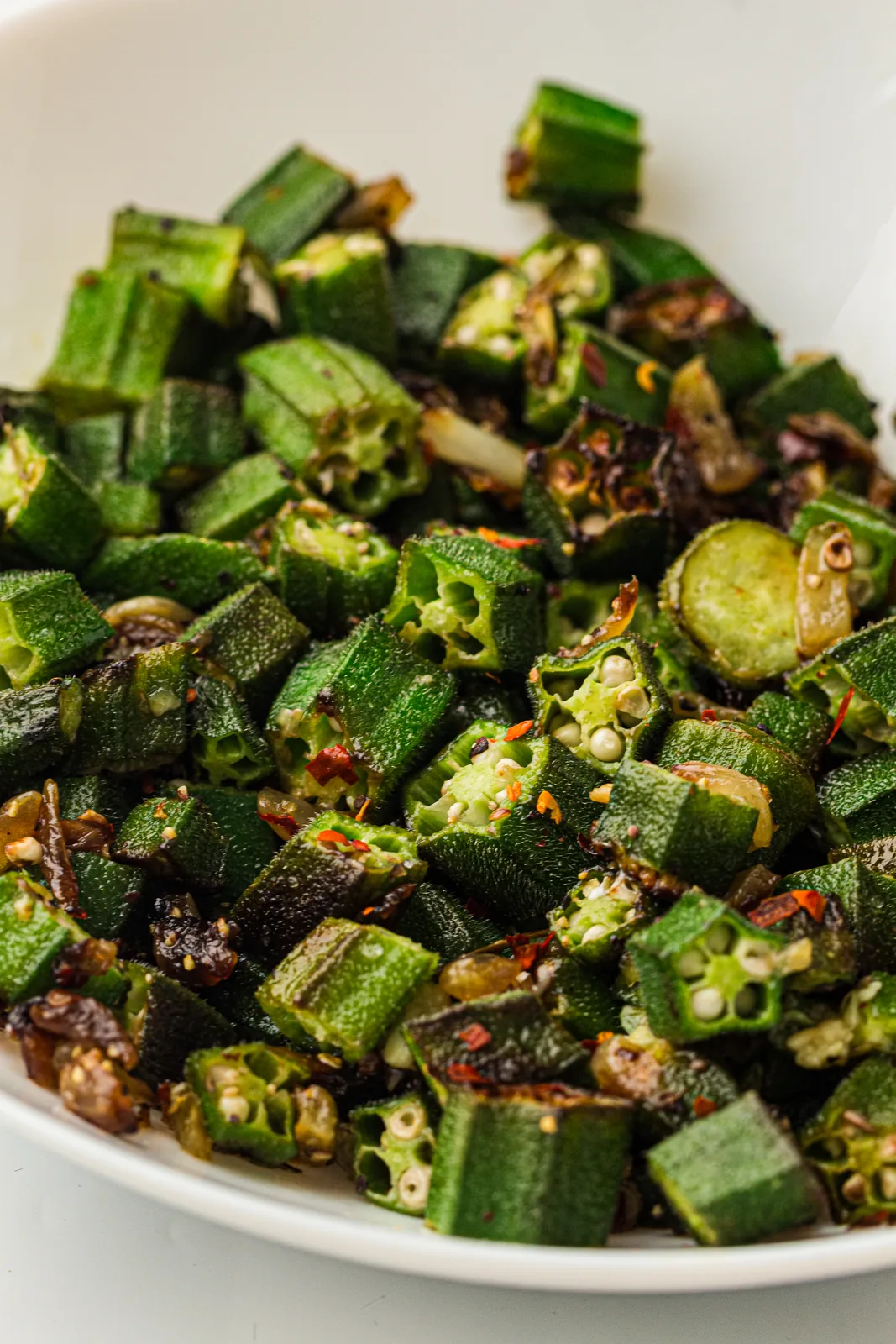 Sauteed okra with red pepper flakes in a white bowl
