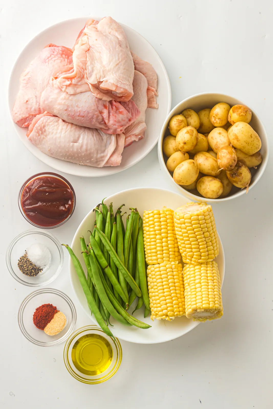 Ingredients for BBQ chicken thighs: chicken, potatoes, green beans, corn, and BBQ sauce