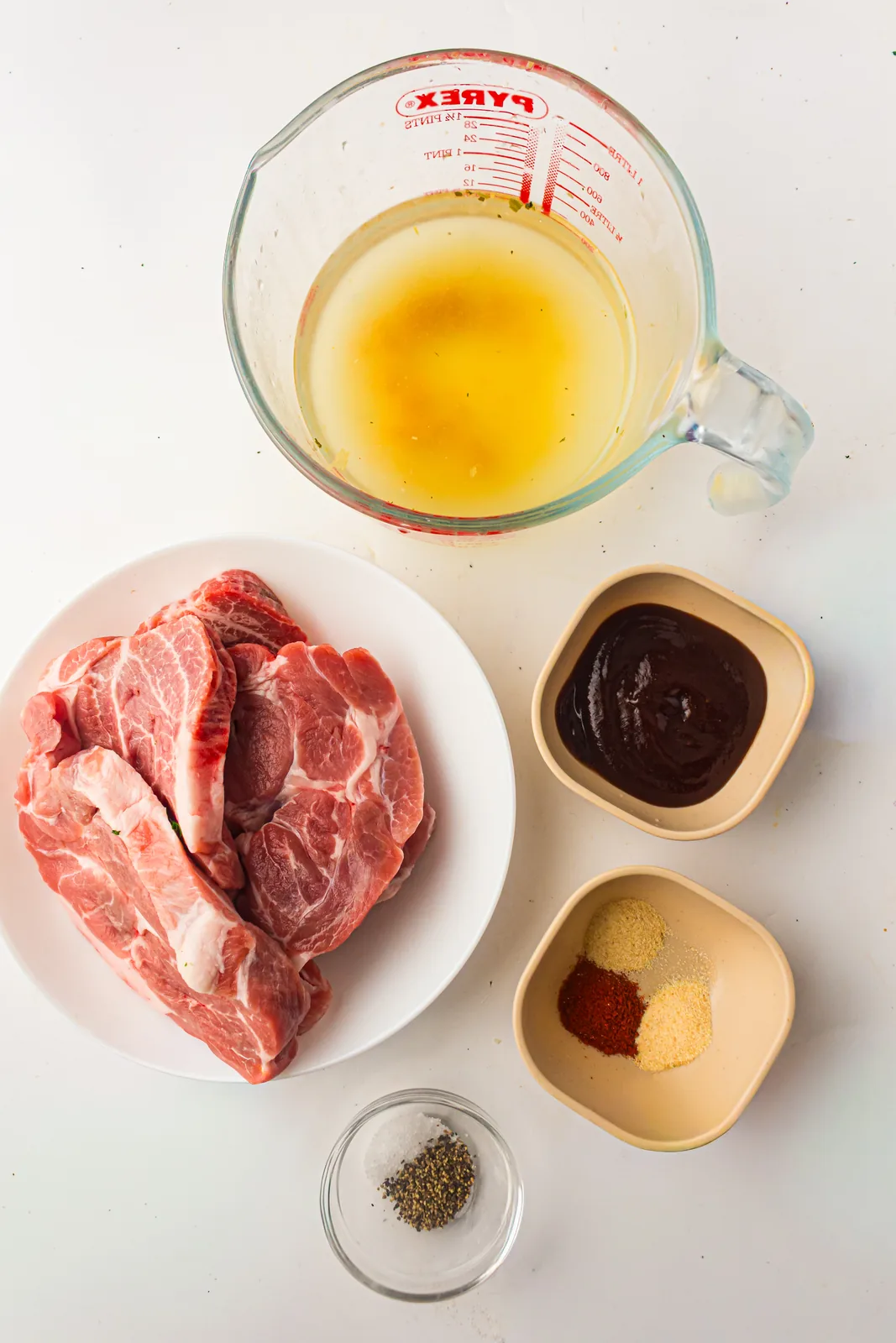 Ingredients for slow cooker pulled pork: pork shoulder, broth, spices, and BBQ sauce