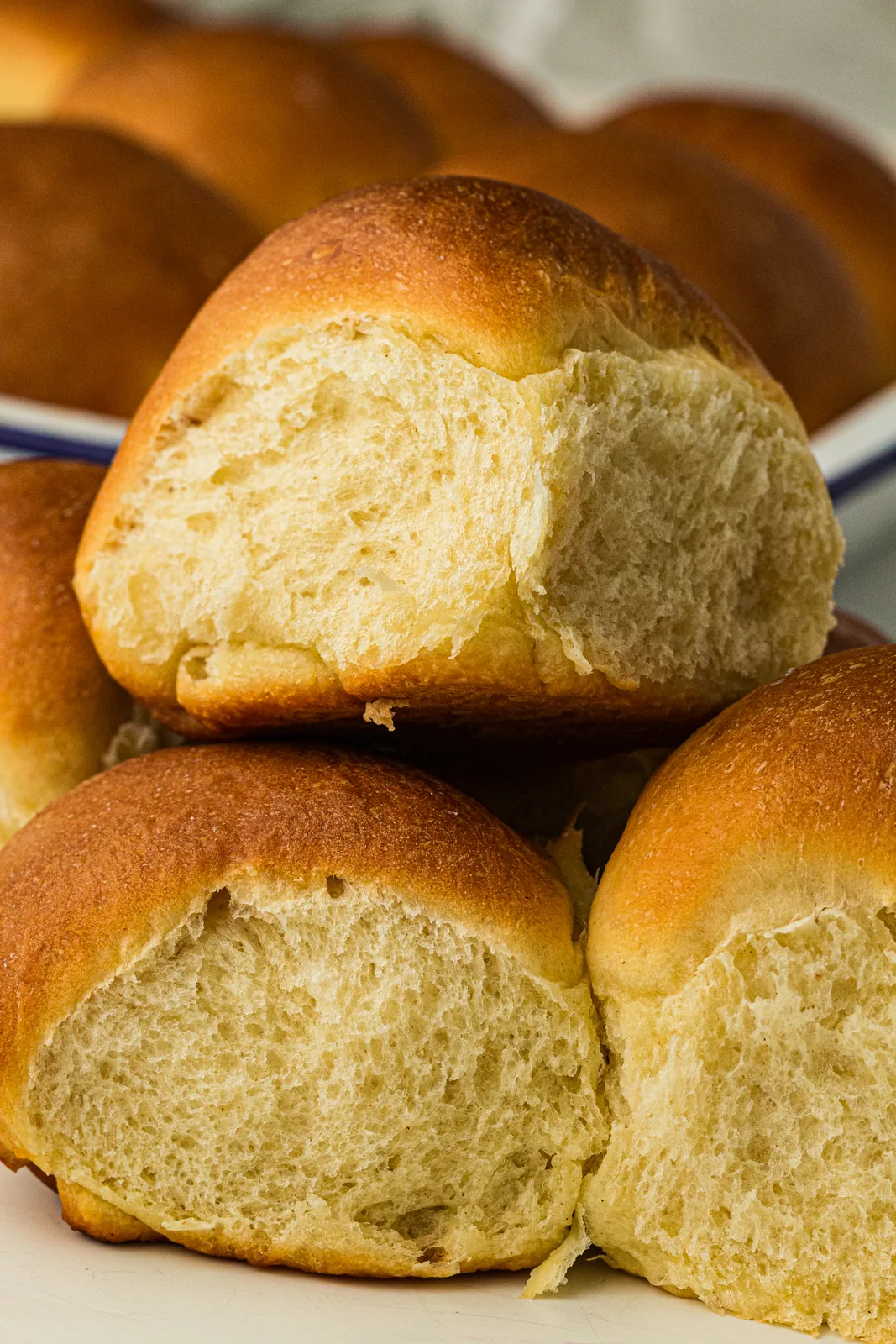 A pile of golden, pull-apart rolls with one torn open to show the fluffy white crumb