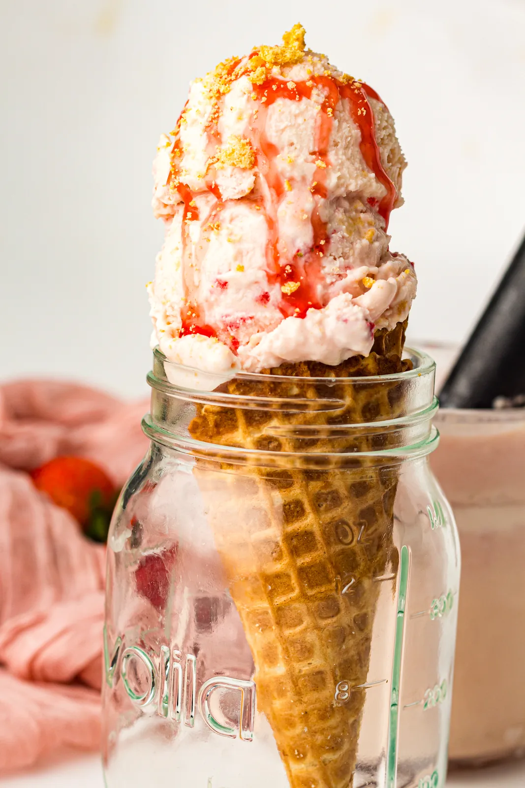 Strawberry cheesecake ice cream on a cone with sauce drizzle