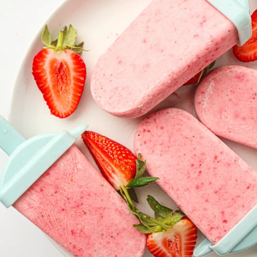 Strawberry popsicles on a plate with fresh strawberries