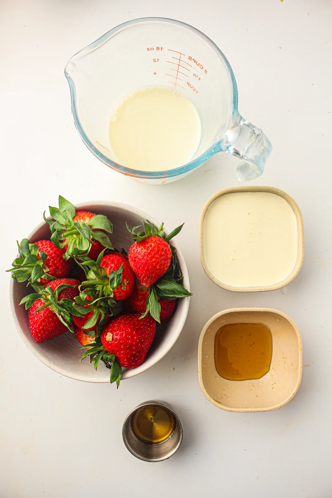 Ingredients for strawberry popsicles: strawberries, honey, milk, cream, and vanilla