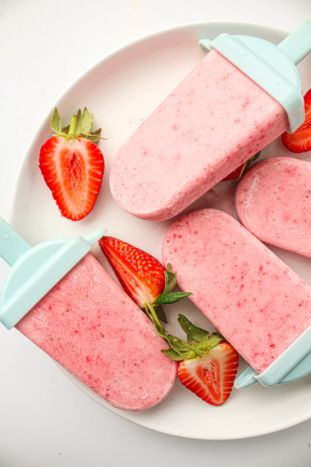 Strawberry popsicles on a plate with fresh strawberries
