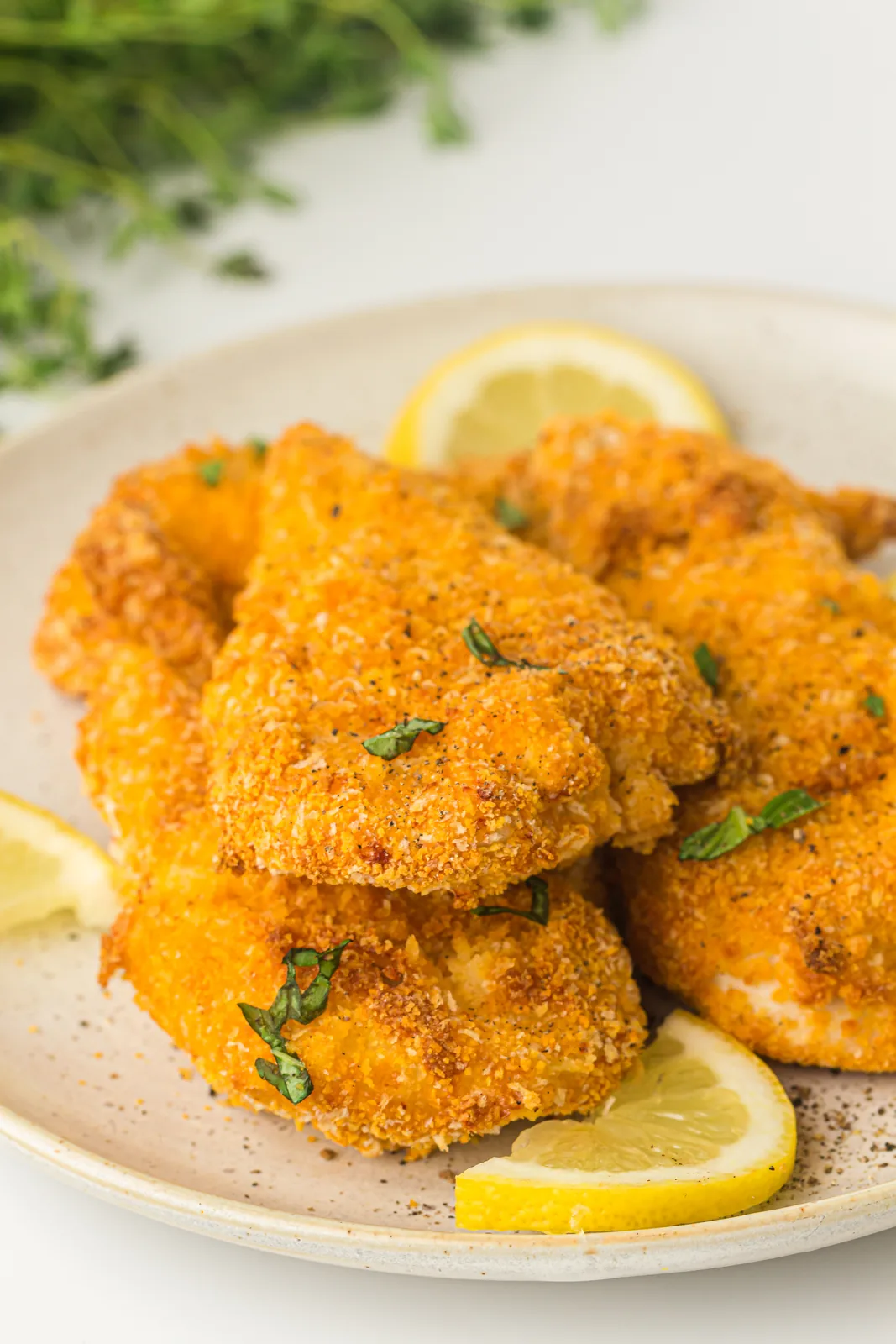 Air fryer chicken cutlets stacked on a plate with lemon