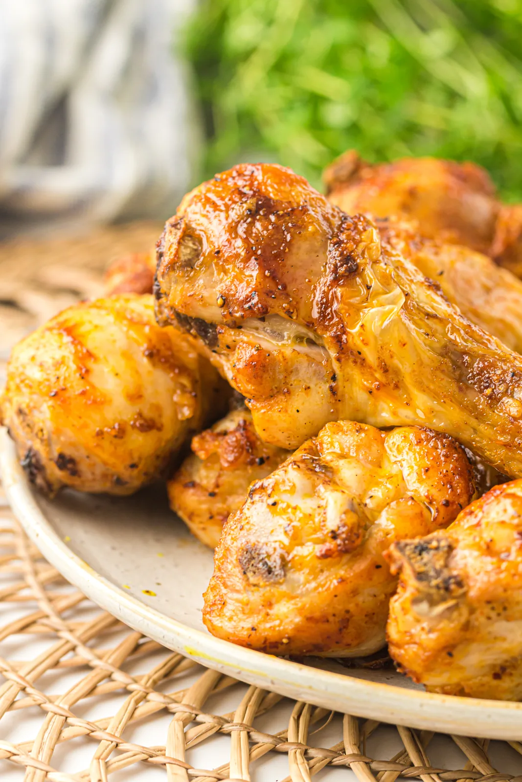 Air fryer chicken drumsticks piled on a plate with crisp golden skin