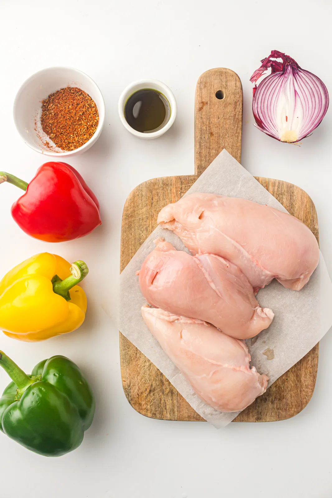 Ingredients for air fryer chicken fajitas: chicken strips, three peppers, red onion and seasoning