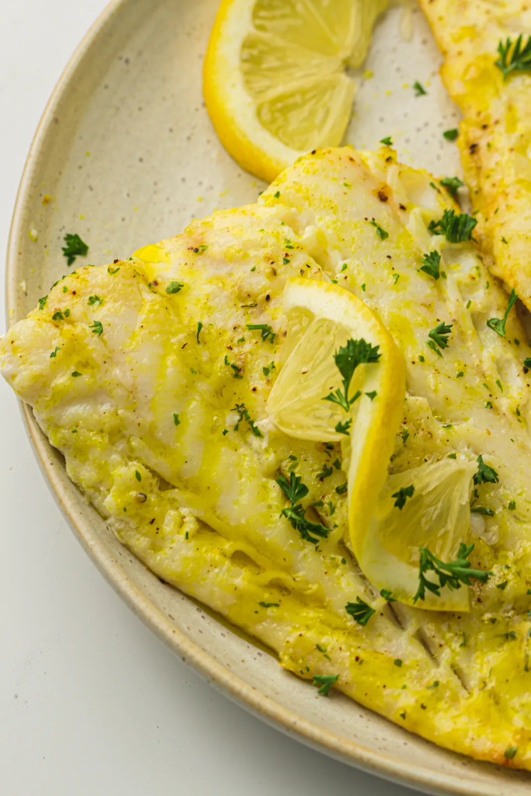 Air fryer cod fillet on a plate with lemon and parsley