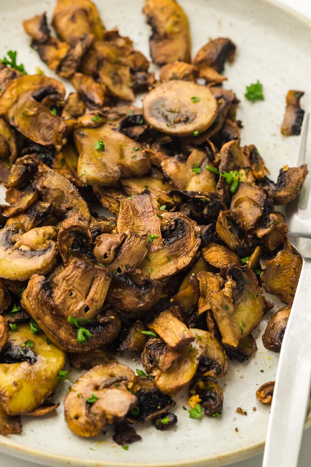 Air fryer mushrooms served on a white plate with a fork