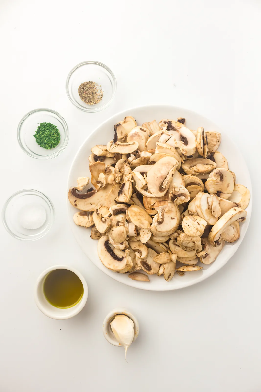 Ingredients for air fryer mushrooms: sliced button mushrooms, oil, garlic, salt, pepper and dried parsley