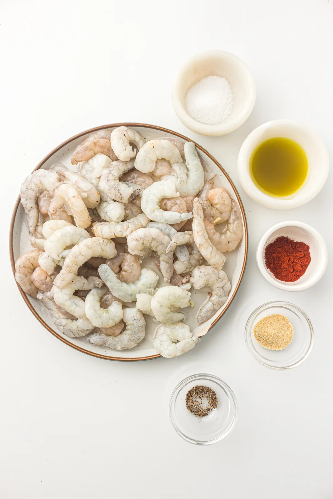 Ingredients for air fryer shrimp: raw shrimp, paprika, garlic powder, oil and lemon